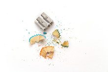 Metal Pencil Sharpener And Colored Sawdust From Pencils On A White Background