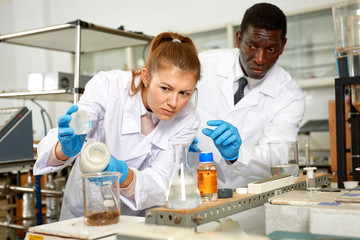 Focused lab technician woman with tubes and worried man  technician