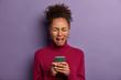 © WHstudio Leushin N - Depressed crying woman holds mobile phone in her hands, wears burgundy turtleneck, upset not to receive message from boyfriend, has no money to call friend, stands with sorrowful expression.