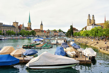 Canvas Print - Grossmunster, St Peter Church and Fraumunster Church, and boats at Limmat River quay in the city center in Zurich, Switzerland. People on the background