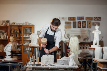 Wall Mural - Stone carver works with wooden hammer and chisel at limestone.