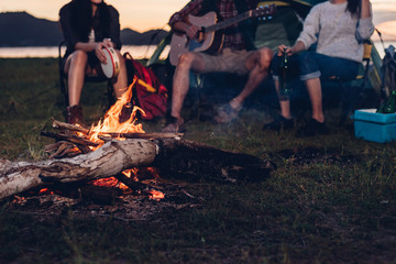 camping tent camp in nature happy friends group night party bonfire and playing guitar together