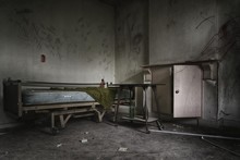 Dramatic Shot Of An Abandoned Prison Room With A Broken Bed And Weathered Windows