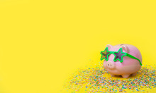 A Pink Piggy Bank In Fun Green Glasses At A Party. Yellow Background.