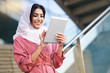 © javiindy - Young Arab woman wearing hijab using digital tablet outdoors