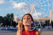 © Smile - Beautiful young woman blowing soap bubbles outdoors