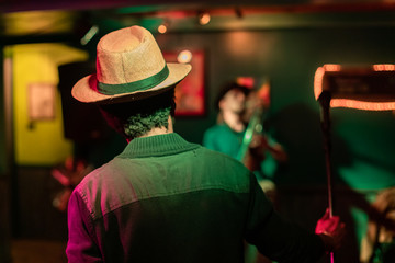 Closeup of male musician holding microphone against artist singing on stage in illuminated auditorium hall at world and spoken word festival