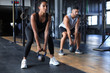 © ty - Fit and muscular couple focused on lifting a dumbbell during an exercise class in a gym.