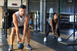 © ty - Fit and muscular couple focused on lifting a dumbbell during an exercise class in a gym.