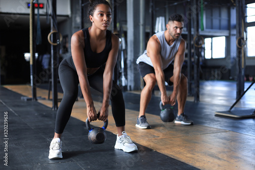 Fotomural Fit and muscular couple focused on lifting a dumbbell during an exercise class in a gym