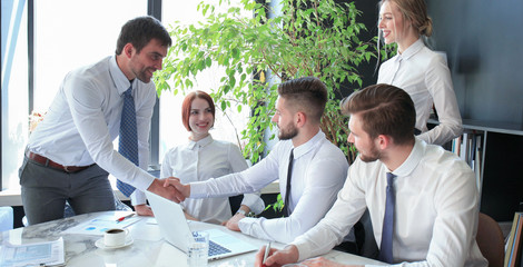 Fototapete - Businessman shaking hands to seal a deal with his partner and colleagues in office.
