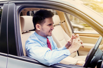 Irritated young businessman driving a car