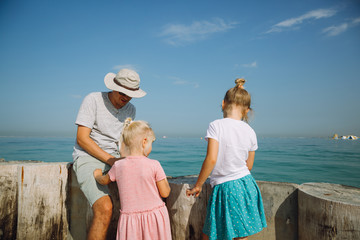 Kids with father at the beach and looking at the sea