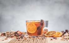 Fruit Tea In Glass Cup With Dry Orange And Cinnamon On Wooden Table, Front View