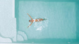 Fototapeta  - Woman relaxing in clear pool water in hot sunny day on Bali villa
