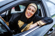 Attractive patient smiling young muslim woman sitting in her car and waiting in traffic jam.