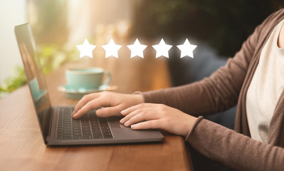 Girl in internet cafe giving high quality rating on laptop