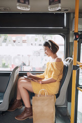 Wall Mural - Beautiful young woman sitting in city bus and writing some notes in notebook.