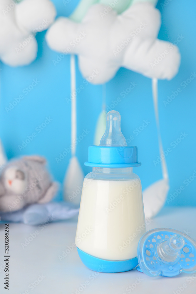 Bottle of milk for baby and pacifier on table