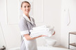 Beautiful chambermaid with clean towels in hotel bathroom