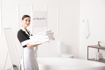 Poster - Beautiful chambermaid with clean towels in hotel bathroom