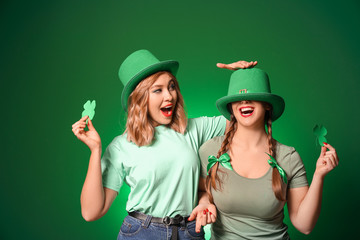 Funny young women on color background. St. Patrick's Day celebration