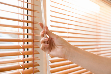 Woman opening blinds on window