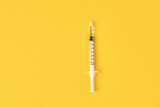 Fototapeta Dmuchawce - Medical syringe on the yellow background, top view with copy space. Vaccination and virus protection concept