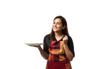 Indian Woman chef wearing apron and holding empty dinner plate with different  facial expressions, standing isolated over white background