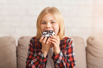 Wall Mural - Girl Enjoying Eating Unhealthy Donut Sitting On Sofa At Home