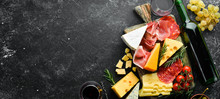 Appetizers Table With Italian Antipasti Snacks And Wine In Glasses. Cheese, Wine, Salami And Prosciutto On A Black Stone Background. Top View. Free Space For Your Text.