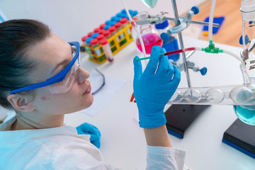 Poster - Young woman in chemical lab Young woman in chemical lab. cience professional pipetting solution into the glass cuvette.