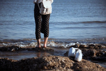 A girl took off her shoes and stood on the reef by the sea