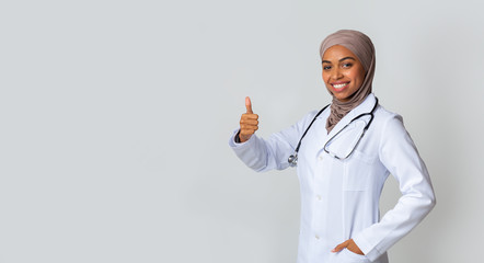 Wall Mural - Portrait Of Friendly Afro Female Doctor In Hijab Gesturing Thumb Up