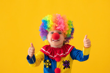 Wall Mural - Funny kid clown playing against yellow background