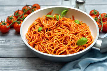 Wall Mural - Close up of spaghetti with tomato suace in a pan on black background