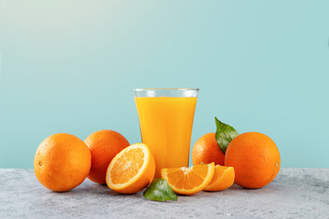 Fresh orange juice glass and oranges on blue background