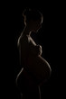© jutaphoto - Beautiful nude pregnant young woman caring her belly. silhouette of a pregnant woman on a black background