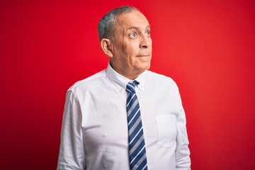 Sticker - Senior handsome businessman wearing elegant tie standing over isolated red background smiling looking to the side and staring away thinking.