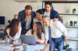 © Krakenimages.com - Group of business workers smiling happy and confident. One of them sitting and partners standing around. Working together with smile on face looking at the laptop at the office