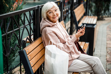 Wall Mural - Happy aged woman with cell phone outdoors stock photo