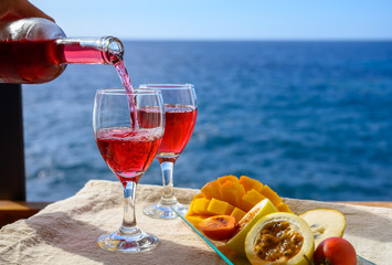 Two glasses with rose wine served outdoor with exotic fruits on tropical island La Palma, Canary islands, Spain with beautiful blue ocean view