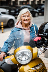 Wall Mural - Jolly elderly female with motorbike stock photo