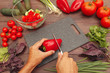 © Boris Bulychev - Cook hands cut fresh bellpepper on a wooden table.