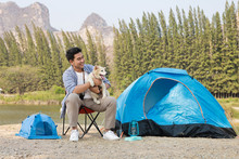 Asian Young Man In Blue Shirt With Cute Puppy Dog Camping On The Lake Hill Mountain View Happy And Enjoy Life