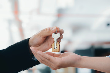 Real estate agent  holding key with house shaped keychain.