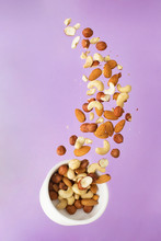 Flying Nuts On A Purple Background: Almonds, Cashew And Hazelnat