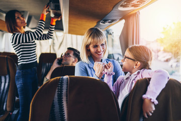 Pregnant woman with her cute little daughter traveling in bus.