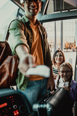 Wall Mural - Young male traveler showing ticket to a bus driver.