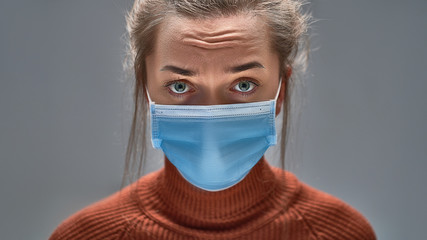 Wall Mural - Unhappy sad woman wearing blue medical protective mask to health protection and prevention during flu virus outbreak, epidemic and infectious diseases